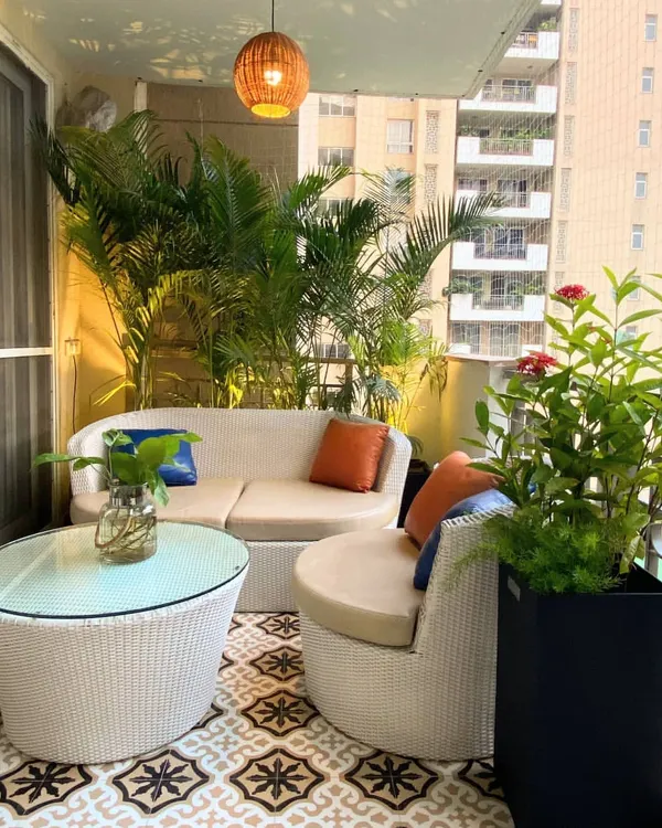 This cozy seating arrangement at our Palm Springs project features a curved outdoor sofa that fits perfectly into the balcony corner. The vibrant cushions add a pop of color against the neutral wicker and lush green backdrop.