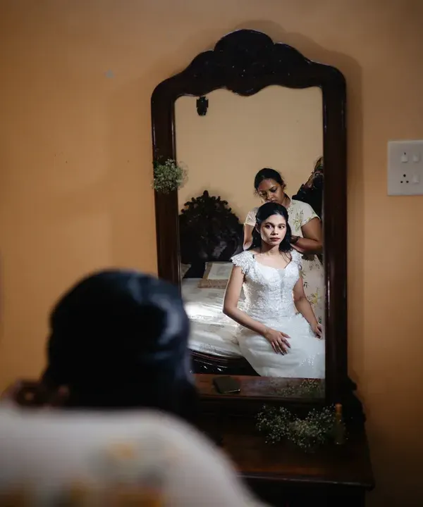 A quiet moment of reflection for the bride as she gets her hair done, seen through the frame of a vintage mirror.