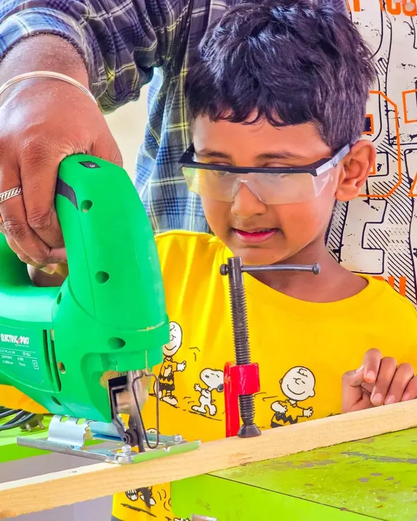 Safety is our top priority as we guide young innovators in using real tools. Here, a camper learns to handle a jigsaw with one-on-one supervision to bring their wooden creation to life.