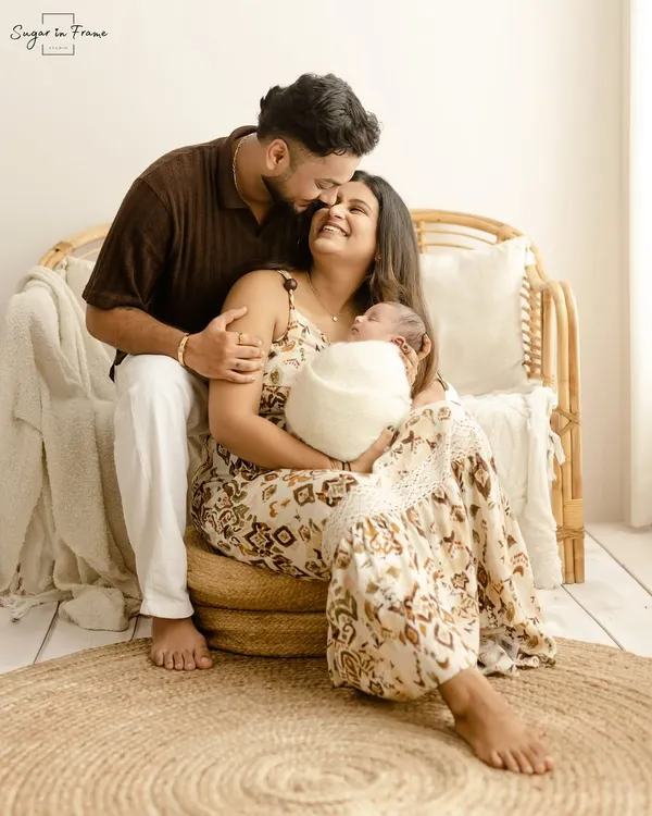 A beautiful family portrait with a newborn. The parents look on with so much love as the mother cradles their sleeping baby, perfectly capturing the joy of the first few days.