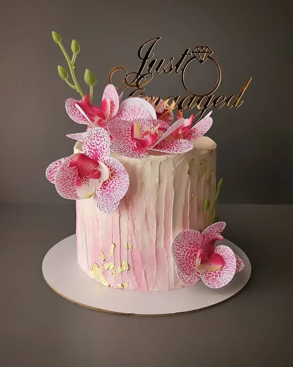 A beautiful pink orchid cake for an engagement. This buttercream cake is decorated with delicate wafer paper orchids and gold leaf accents for a touch of elegance.