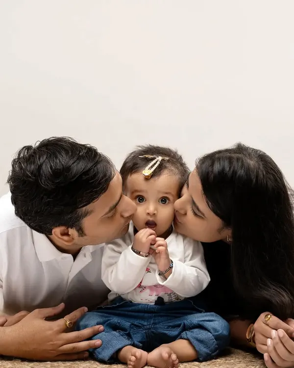 We believe in capturing pure love. This classic family portrait, with parents showering their little one with affection against a clean studio backdrop, is a timeless memory we love to create.