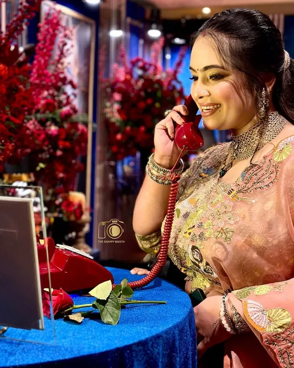A perfect match for a glamorous event. A guest enjoys leaving a message on the Retro Red phone, surrounded by lush floral arrangements that create a truly luxurious and photogenic corner at your reception.