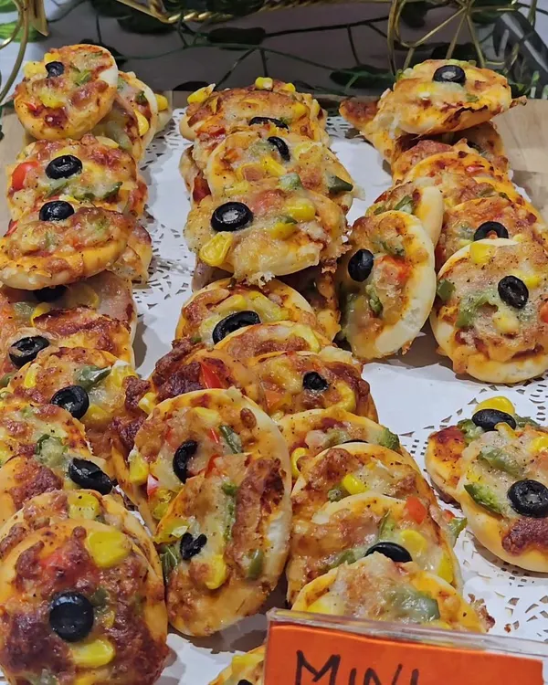 A platter of delicious mini vegetable pizzas, topped with corn, olives, and bell peppers. These bite-sized treats are perfect for little hands and are always a party favorite.