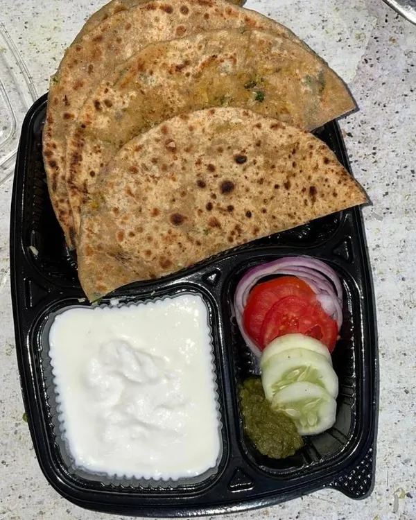 A simple and satisfying meal of hot, layered parathas served with cool dahi and a side of fresh salad. This is a classic North Indian comfort food option, perfect for lunch or dinner.