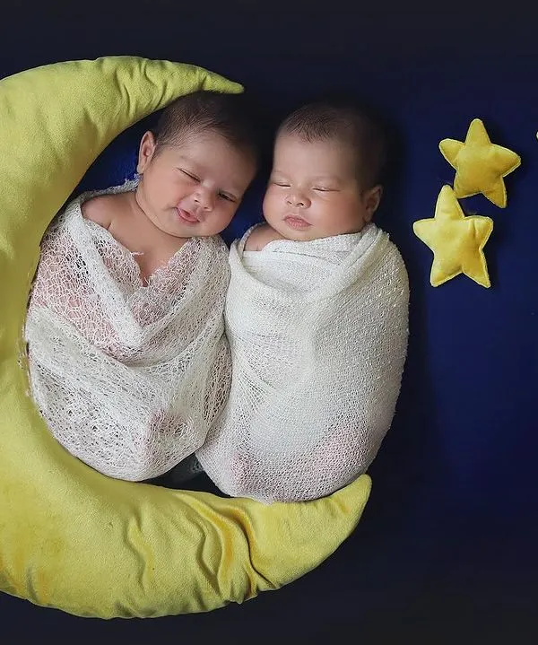Two little stars sleeping on a crescent moon. This celestial theme is one of my favorites for twin newborn photography. The simple white wraps and dark blue background make the babies the shining center of attention.