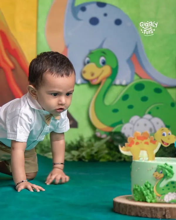 That moment of curiosity just before the fun begins! This little one is eyeing his dinosaur-themed cake, ready for his first taste of birthday sweetness.