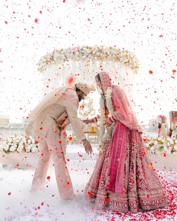A whirlwind of love and petals. I styled this moment to feel like a dream, with a custom-coordinated pastel palette for the couple's outfits and a cloud of smoke to create an ethereal, romantic atmosphere for their varmala ceremony.