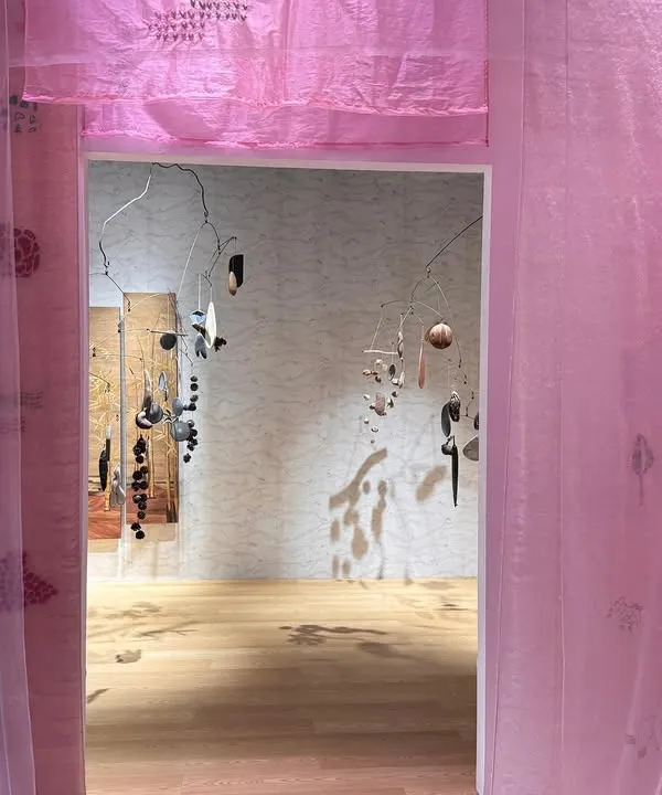 An entrance into the 'Feel More' installation, where layers of translucent pink fabric create a soft, ethereal threshold. The hand-printed patterns whisper stories of nature's simplicity.