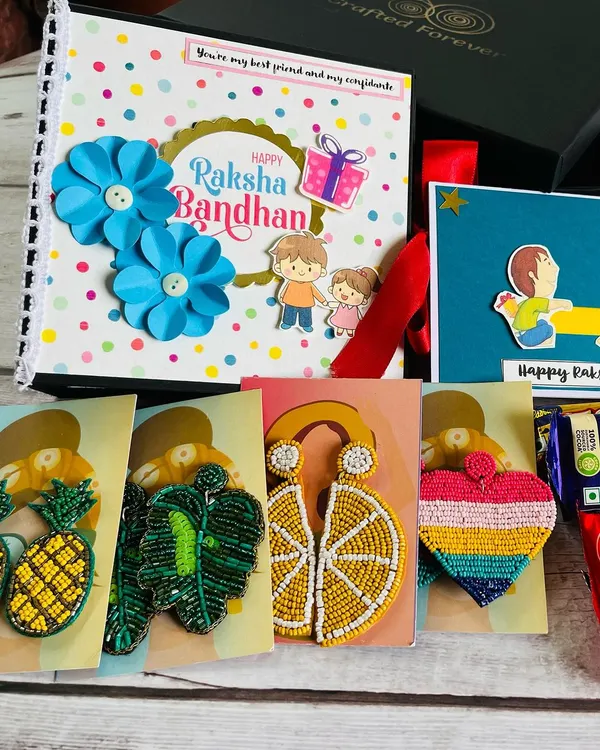 A complete Rakhi celebration in one box! This hamper includes a custom scrapbook, a variety of our popular handmade beaded earrings, a greeting card, and chocolates. It’s the perfect surprise for a sister.