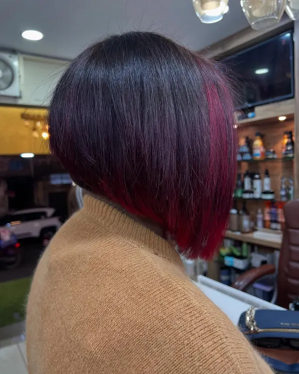 A sharp, angled bob with a secret splash of color. This look features a vibrant magenta panel underneath, adding an edgy and surprising element to a classic cut.