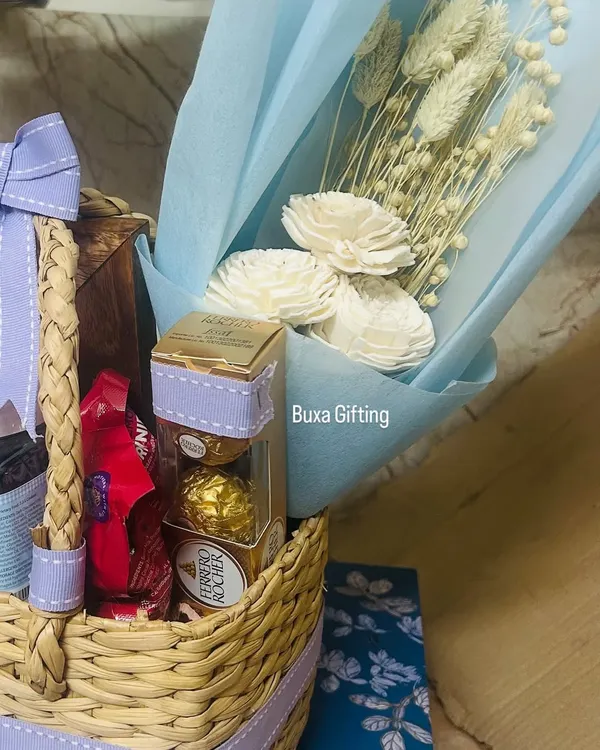 A close-up of a romantic birthday hamper for a fiancée. It includes her favorite white dried flowers, Ferrero Rocher chocolates, and other treats in a beautiful jute basket.