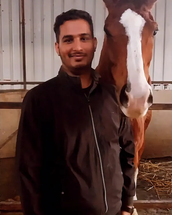A member of our team shares a moment with Vikrant, one of our most loved horses, inside the stable.