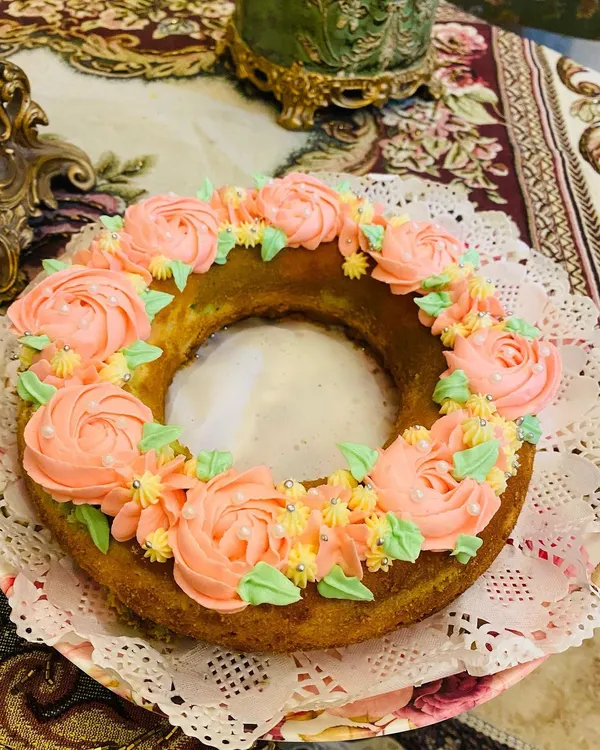 This is my Ribbon Bundt cake, decorated with a beautiful wreath of pink buttercream rosettes and delicate sprinkles. It's perfect for a special tea party.