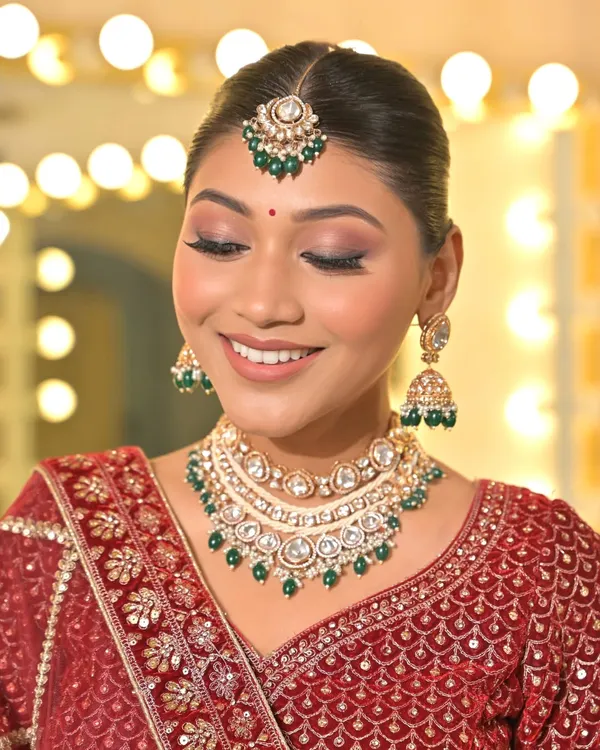 A perfect close-up of a classic Kundan set featuring green bead drops. This image clearly shows the intricate setting of the stones in the necklace, earrings, and maang tikka.