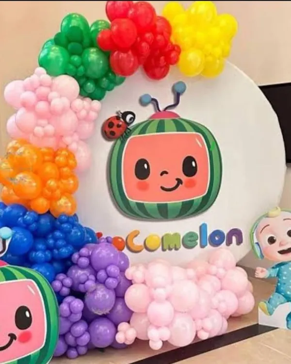 A vibrant Cocomelon themed decoration. This setup features a large circular backdrop with the Cocomelon logo, character cutouts, and a colorful balloon garland that mimics the show's bright and cheerful aesthetic.