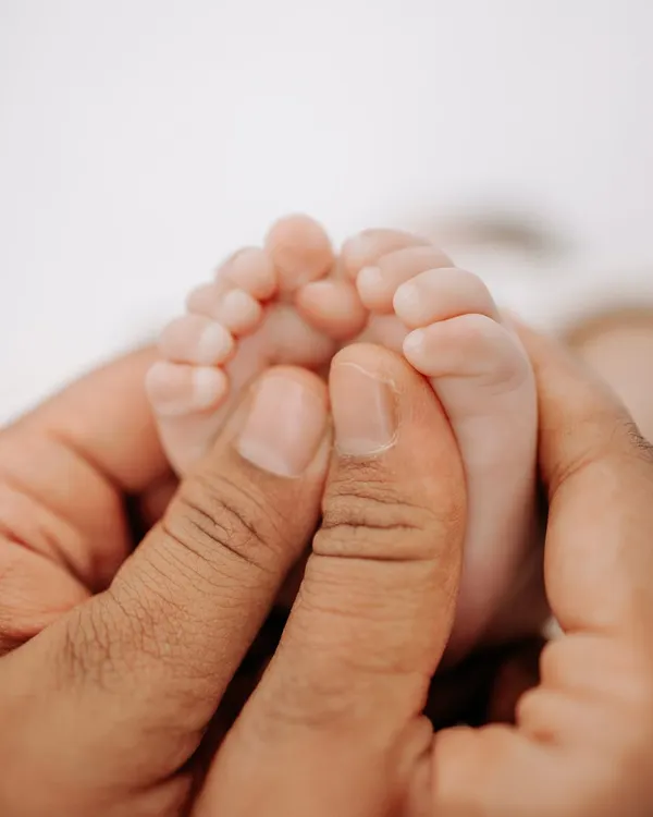 A parent's hands gently holding their newborn's tiny feet. This macro shot is a powerful reminder of how small and precious new life is.