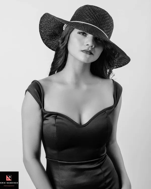 A black and white portrait of a woman in a black dress and a wide-brimmed hat that shadows her eyes. This shot is about mystery and timeless elegance, using monochrome to emphasize form and mood.