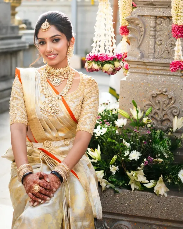 Our bride Hima is the picture of muhurtham elegance in this gold tissue Kanchivaram saree. I designed a matching hand-embroidered blouse to create a timeless and radiant bridal look.