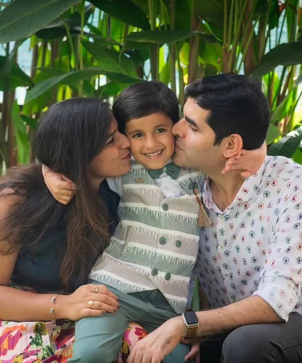 There's nothing sweeter than kisses from mom and dad. This candid family portrait is overflowing with love and affection, captured during an outdoor birthday celebration.