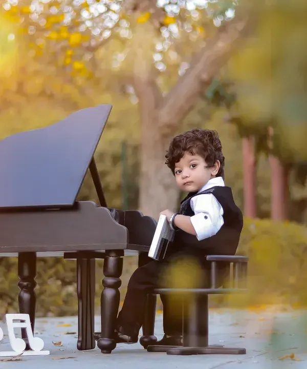 This is our 'Mini Musician' theme, perfect for capturing your little one's budding star quality. I set up this outdoor scene with a miniature piano to create a classic, timeless portrait for a one-year-old's milestone photoshoot.