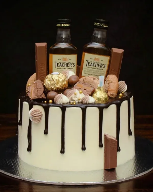 This is my signature loaded drip cake, perfect for a milestone birthday. It features a rich chocolate drip, and is topped with miniature whiskey bottles, Ferrero Rocher, KitKats, and other chocolatey treats.