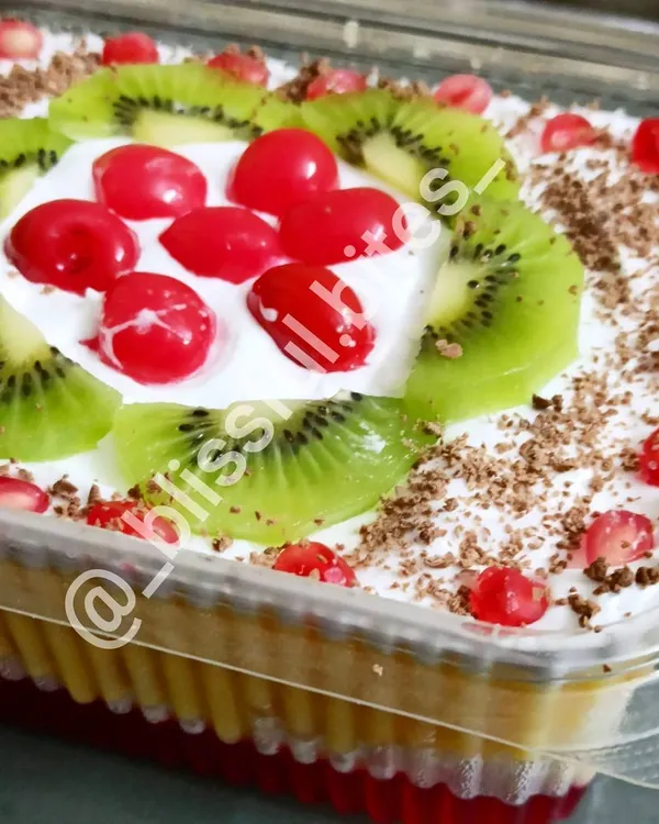 My Mixed Fruit Trifle is a true crowd pleaser. This large party tray shows the beautiful layers of jelly, custard, cake, and fresh cream, topped with vibrant kiwi, cherries, and pomegranate seeds.