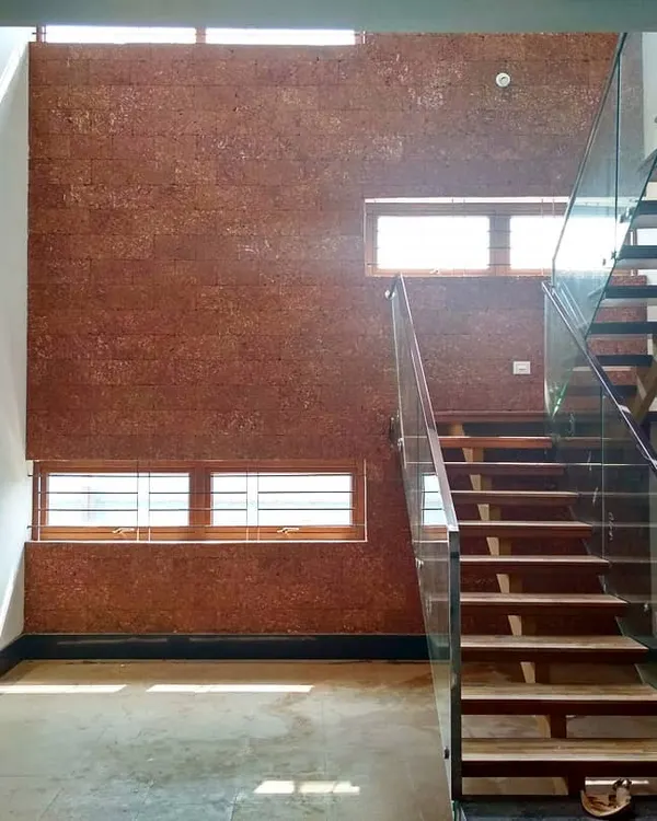 This spacious double-height courtyard is the heart of one of our residential projects in Bengaluru. The combination of a laterite-clad wall, a floating staircase with glass railings, and circular skylights creates a dynamic play of light and natural texture.