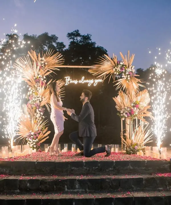 A breathtaking proposal setup complete with a custom floral arch, a neon sign, and dramatic cold pyro fireworks. We design these milestone moments to be as unforgettable as the love story they celebrate.