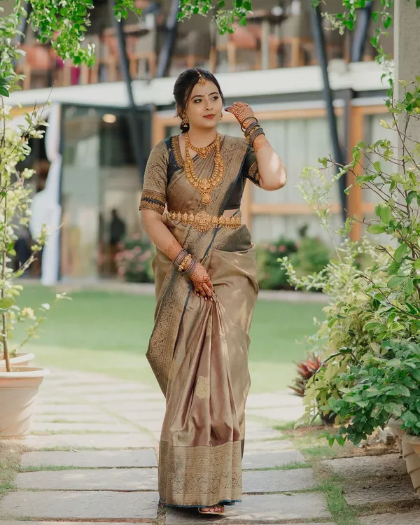 A full-length portrait of a South Indian bride in a stunning silk saree. We captured her in a beautiful garden setting, highlighting the elegance of her traditional attire and gold jewelry.