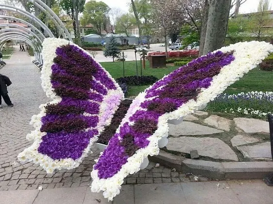 A large, custom-made butterfly sculpture created entirely from artificial flowers. This type of artistic installation is perfect for public gardens, events, or as a unique photo opportunity.