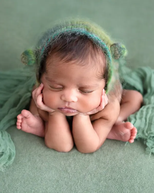 The adorable "froggy pose" is a client favorite, and it's created with the utmost care. This is a composite image, meaning the baby is supported by hands at all times to ensure complete safety while achieving this sweet, curled-up look.