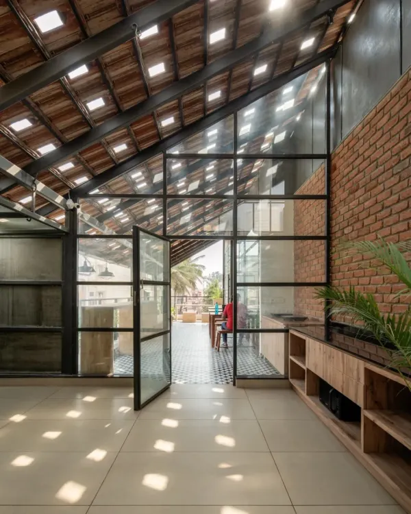 For our Earthen Spirit project, we designed this open terrace to be a hub of activity. The sloping roof features traditional Mangalore tiles with glass inserts, a design that scatters natural light across the floor in shifting patterns. This approach creates a bright, dynamic atmosphere that changes throughout the day, connecting the indoor space with the rhythm of the sun.