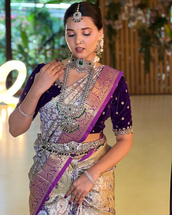 This grand silver-finish necklace set with green stones makes a powerful statement. Paired with a deep purple velvet blouse, it creates a look of pure royalty and modern elegance.