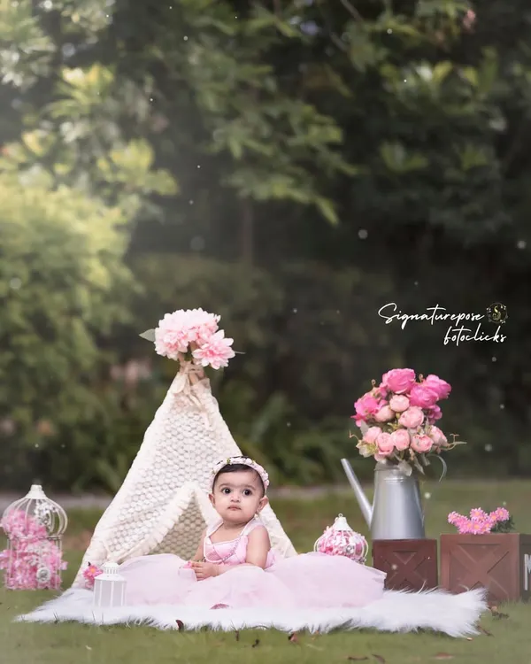 A little princess in her outdoor castle. This beautiful shot combines a whimsical teepee setup with the natural beauty of a park, creating a perfect fairytale scene for a one-year-old.