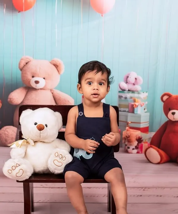 Before the smash. This little one is looking sharp in his overalls, posing in our teddy bear-themed first birthday setup before the cake comes out.