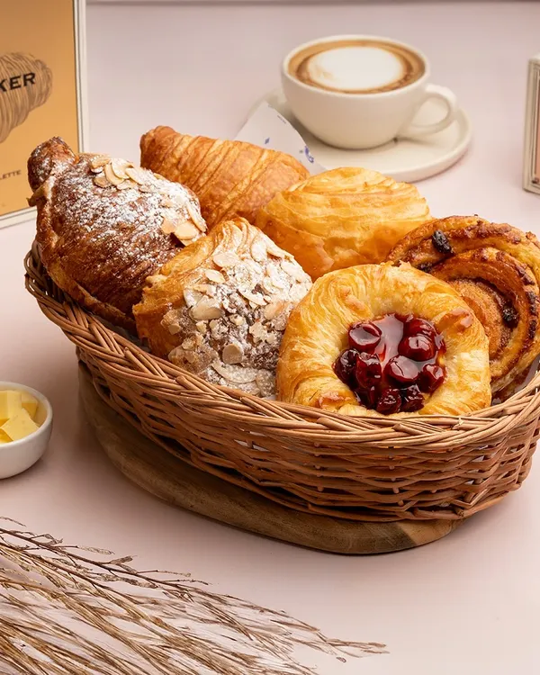 A basket full of my morning bakes. This assortment includes a classic croissant, almond croissant, pain aux raisins, and a cherry Danish, all baked fresh.