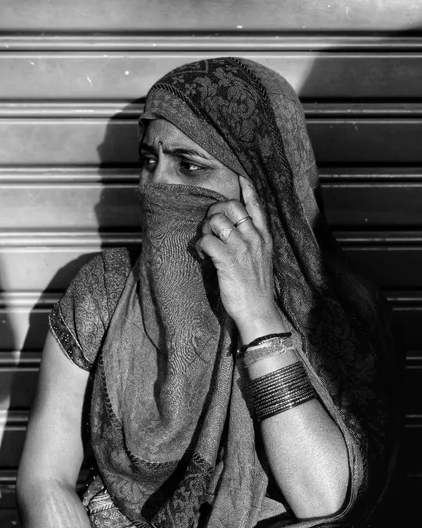 The play of light and shadow from a shuttered storefront created the perfect natural frame for this street portrait. Her partially covered face and direct gaze create a sense of mystery and strength, a moment of quiet dignity I was fortunate to witness.