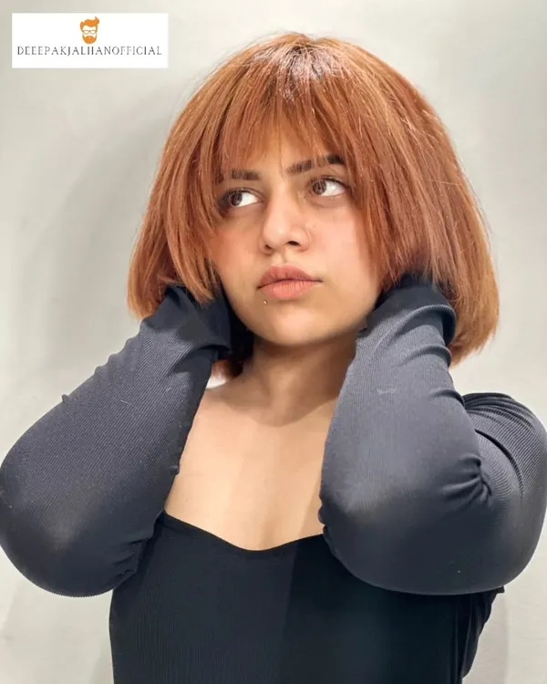 This edgy copper brown bob is a statement. The color is vibrant and the textured bangs are designed to sharpen the jawline and frame the face.