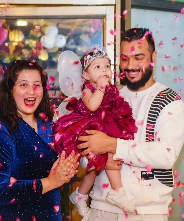 A perfect family photo capturing the joy of a first birthday. The confetti shower adds a dynamic and celebratory feel to this happy moment.