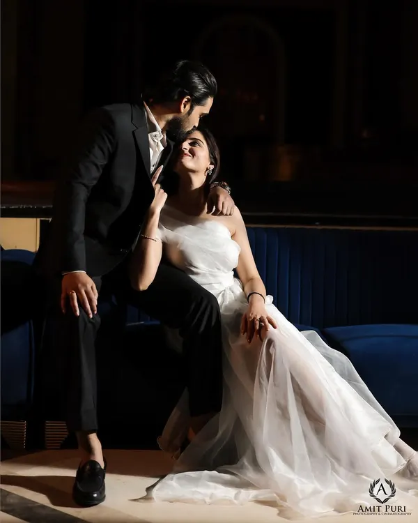 A moment of pure Hollywood glamour. The dramatic lighting, the elegant white dress against the dark suit, and the intimate pose create a cinematic and passionate portrait.