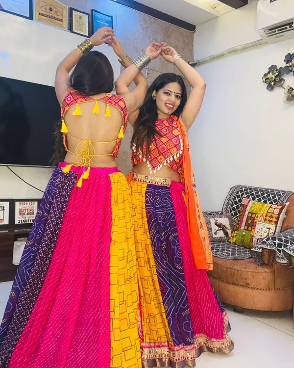 Two friends ready for Garba night in our colorful patchwork lehengas. The backless blouse design with tassels adds a playful and traditional touch.