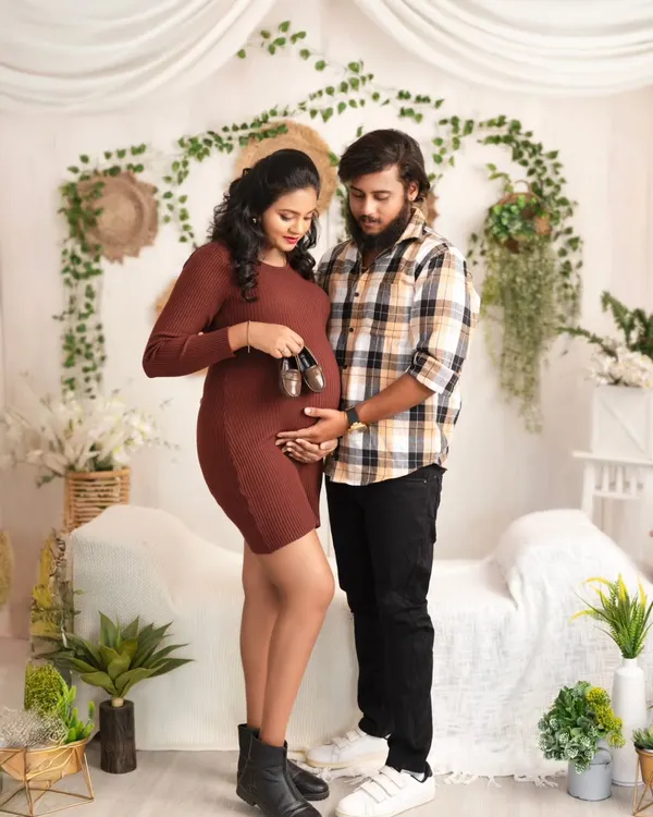 A sweet moment for the parents-to-be. They hold a tiny pair of baby shoes over the bump, a classic and heartwarming pose in our cozy, boho-chic studio setup.