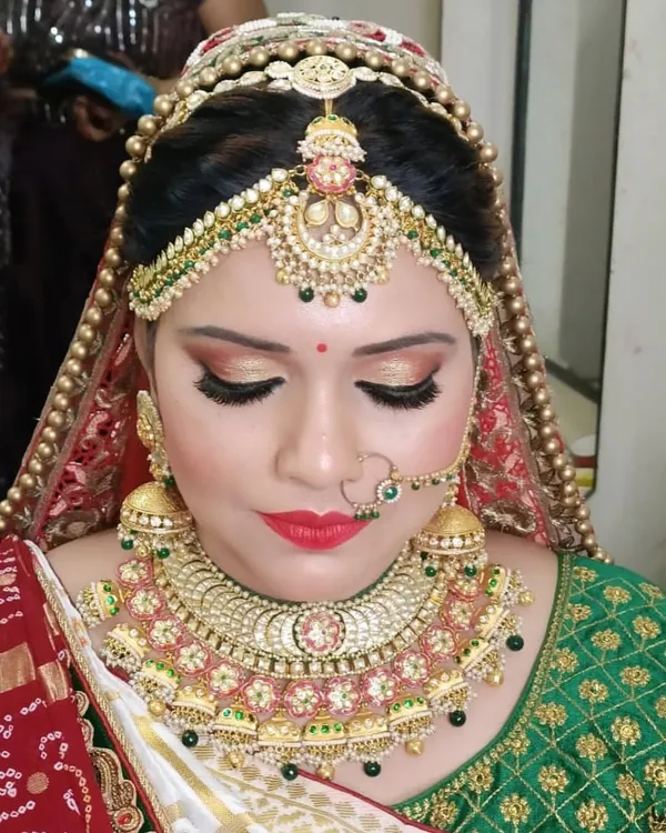A complete and traditional bridal look featuring a heavy choker, matching jhumkas, nath, and an elaborate matha patti that frames the face beautifully.