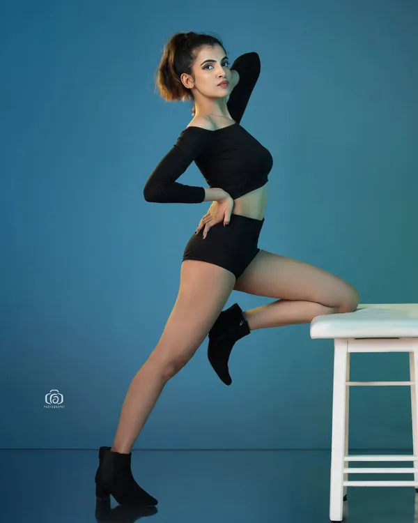 A dynamic pose captured against a vibrant blue gelled background. The reflective studio floor adds another layer of dimension, making this a powerful shot for a contemporary model portfolio.