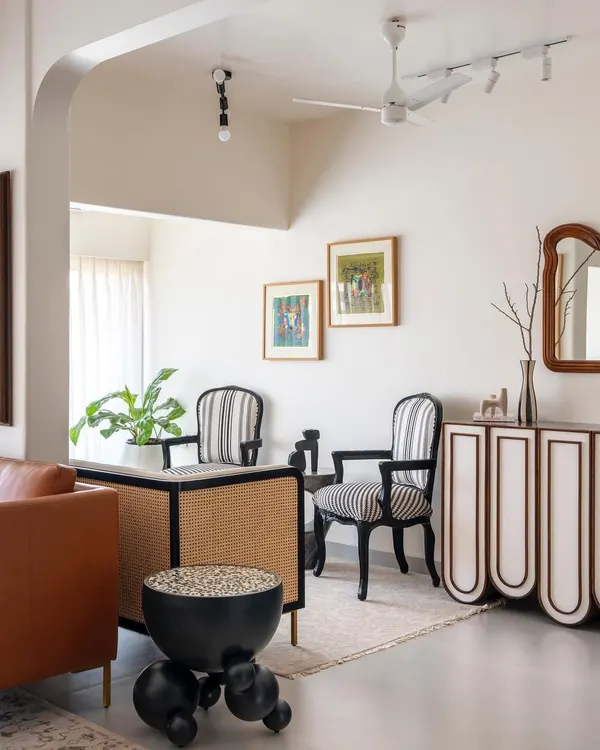 This corner of the living room showcases our approach to custom furniture design. The striped chairs, cane-detailed desk, and sculptural side table are all designed by us to be geometric and abstract, adding character against the muted white walls.