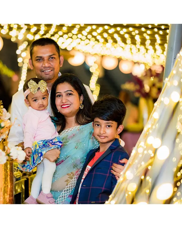 A beautiful family portrait taken during a birthday celebration, with festive lights creating a warm, magical background.