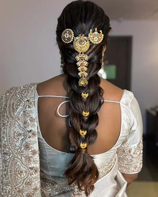 This is a classic South Indian bridal braid, also known as a 'poola jada'. I've adorned this thick, traditional choti with intricate gold temple jewelry for a truly divine look.