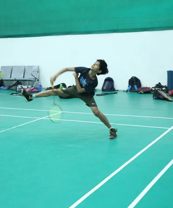 A young player mid-flight, executing a powerful jump smash. We train our athletes to be aggressive and confident in their attacking shots.