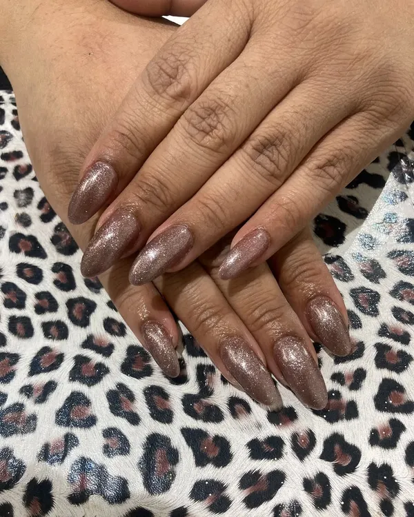 Long, almond-shaped nail extensions are perfect for creating a dramatic and elegant look. This set is finished with a sparkling bronze glitter gel polish that catches the light beautifully.